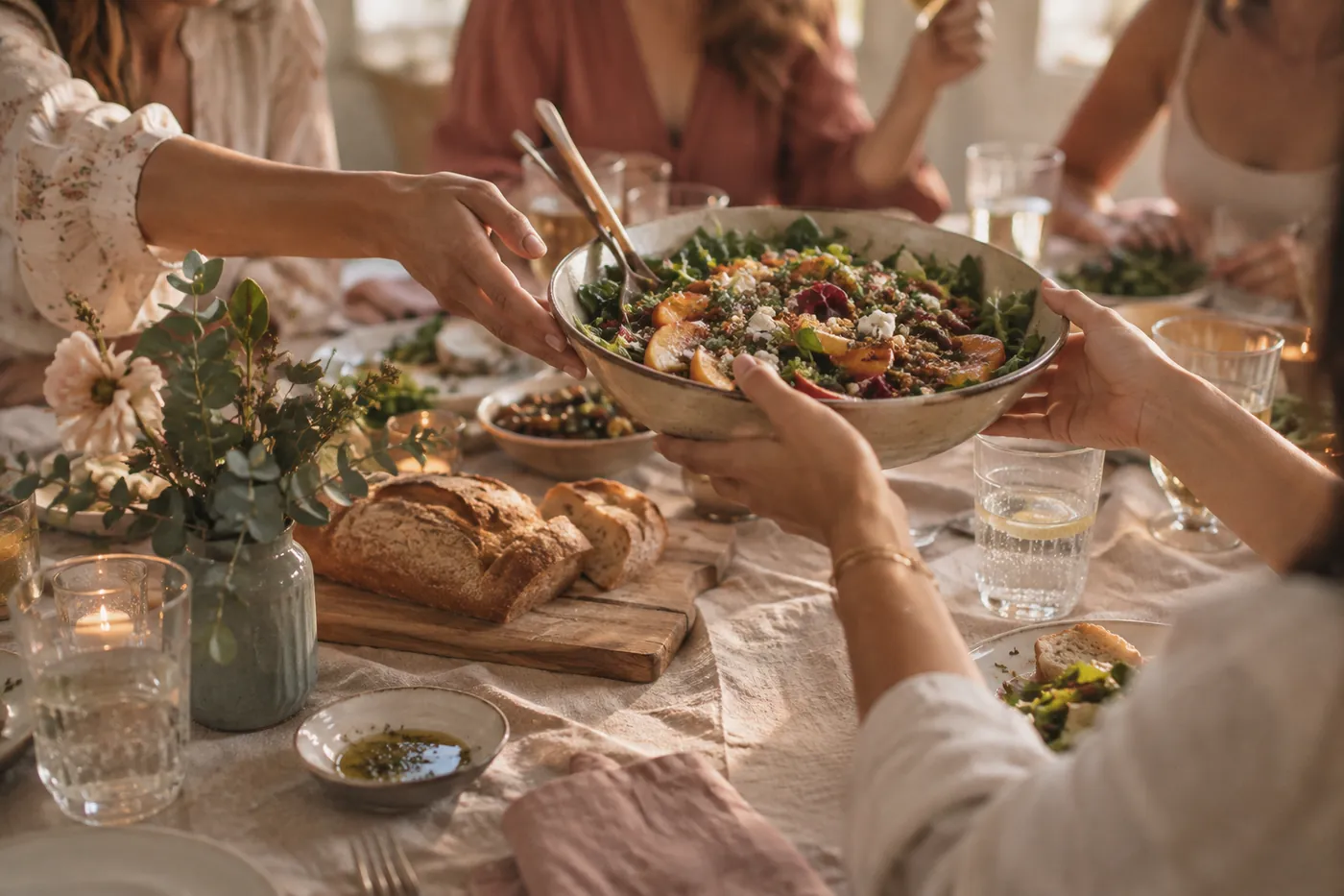 Freundinnen reichen sich beim gemeinsamen Essen eine Salatschüssel